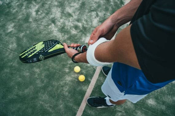 Een sporter die een padelracket vasthoudt, klaar om te spelen op de padelbaan, omringd door enthousiaste fans.